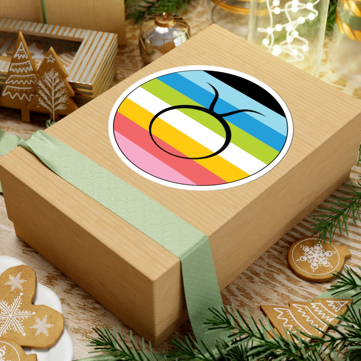 Gift box with a green ribbon on a festive background with cookies and Christmas decorations. Taurus Queer pride sticker centered on the box.