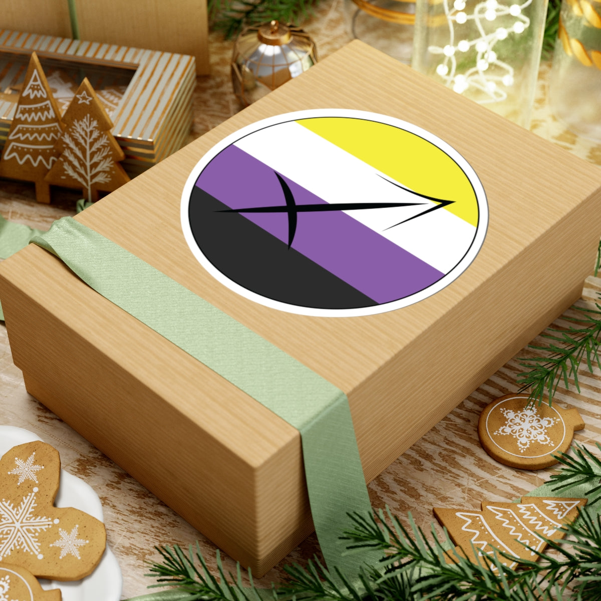 Gift box with a green ribbon on a festive background with cookies and Christmas decorations. Sagittarius Nonbinary pride sticker centered on the box.