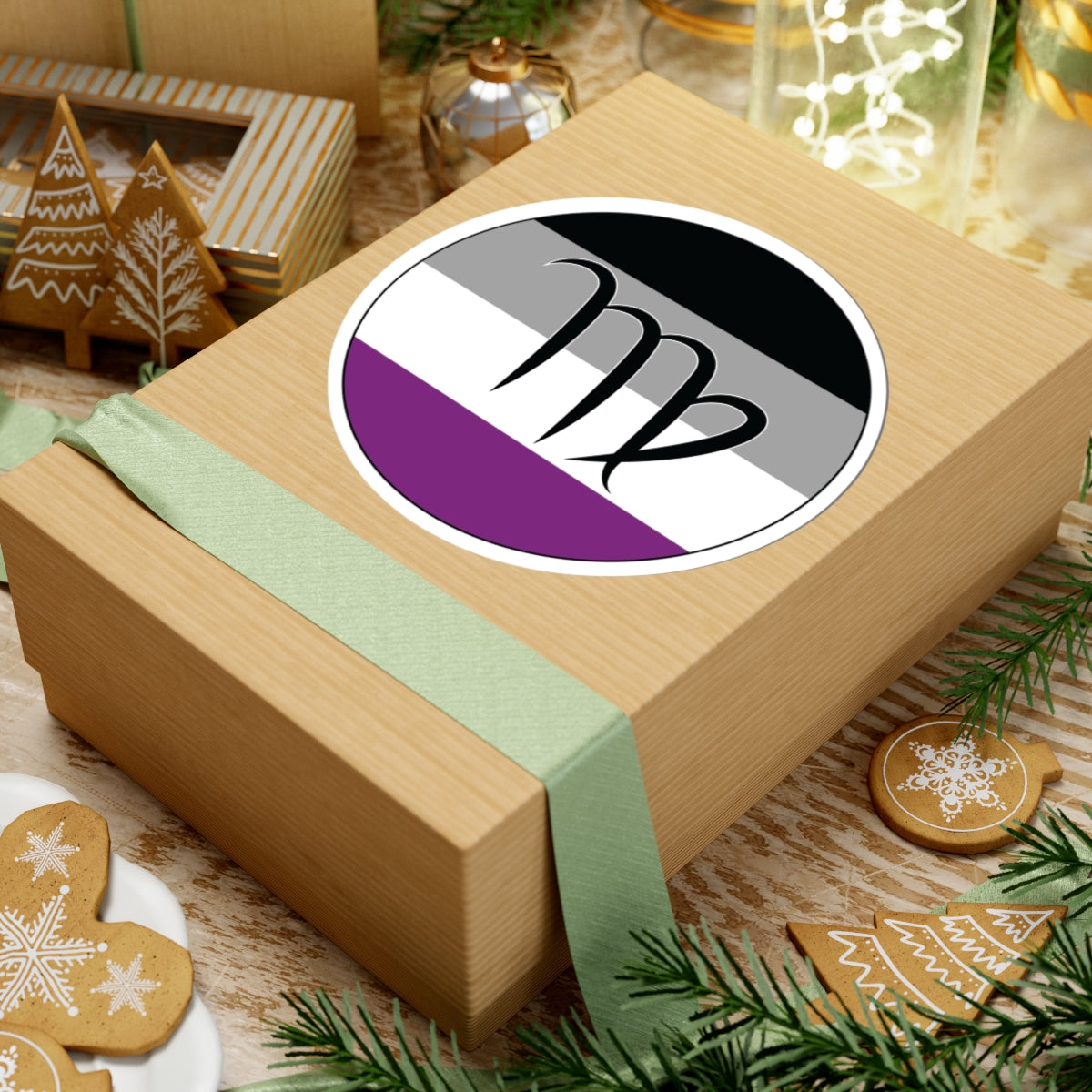 Gift box with a green ribbon on a festive background with cookies and Christmas decorations. Virgo Asexual pride sticker centered on the box.