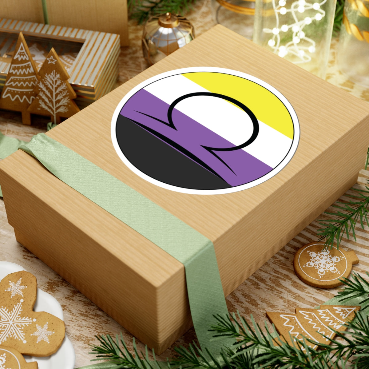 Gift box with a green ribbon on a festive background with cookies and Christmas decorations. Libra Nonbinary pride sticker centered on the box.