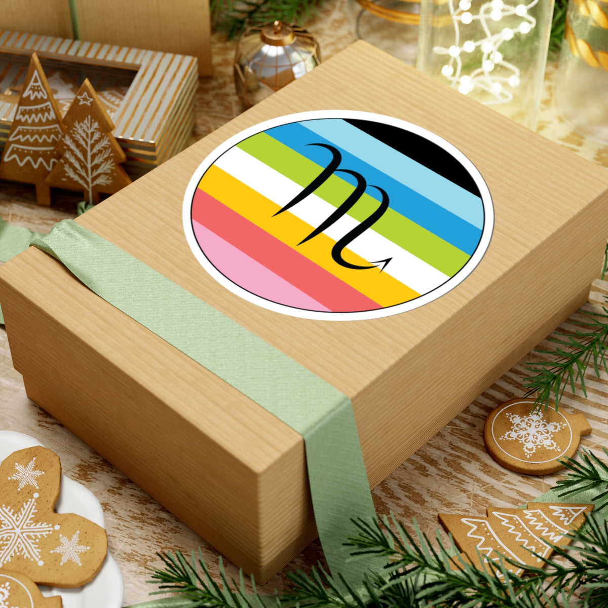 Gift box with a green ribbon on a festive background with cookies and Christmas decorations. Scorpio Queer pride sticker centered on the box.