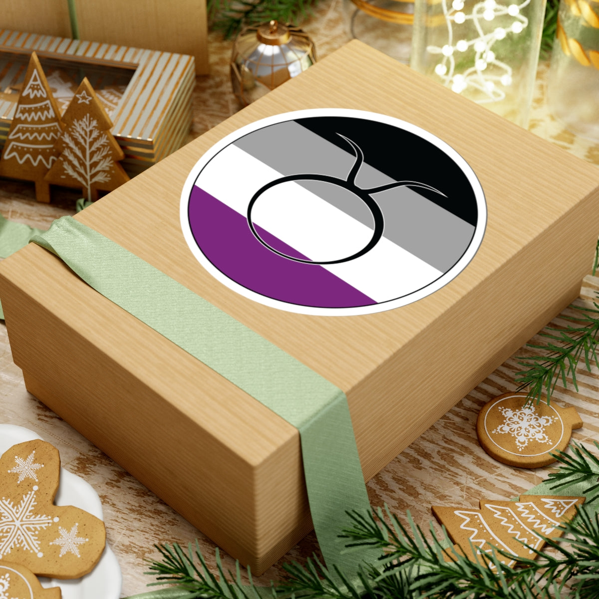 Gift box with a green ribbon on a festive background with cookies and Christmas decorations. Taurus Asexual pride sticker centered on the box.