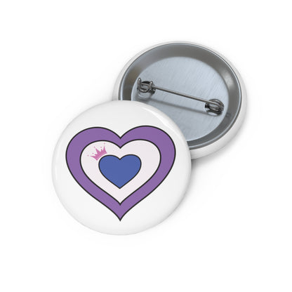 Front and back view of a white circular button with a drag flag inspired heart-shaped image. The image has three nested hearts colored lavender, white and blue with a pink crown in the left side of the white sections. The button is shown on a white background.