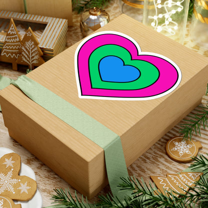 Gift box with a green ribbon on a festive background with cookies and Christmas decorations. Heart-shaped Polysexual pride sticker centered on the box.