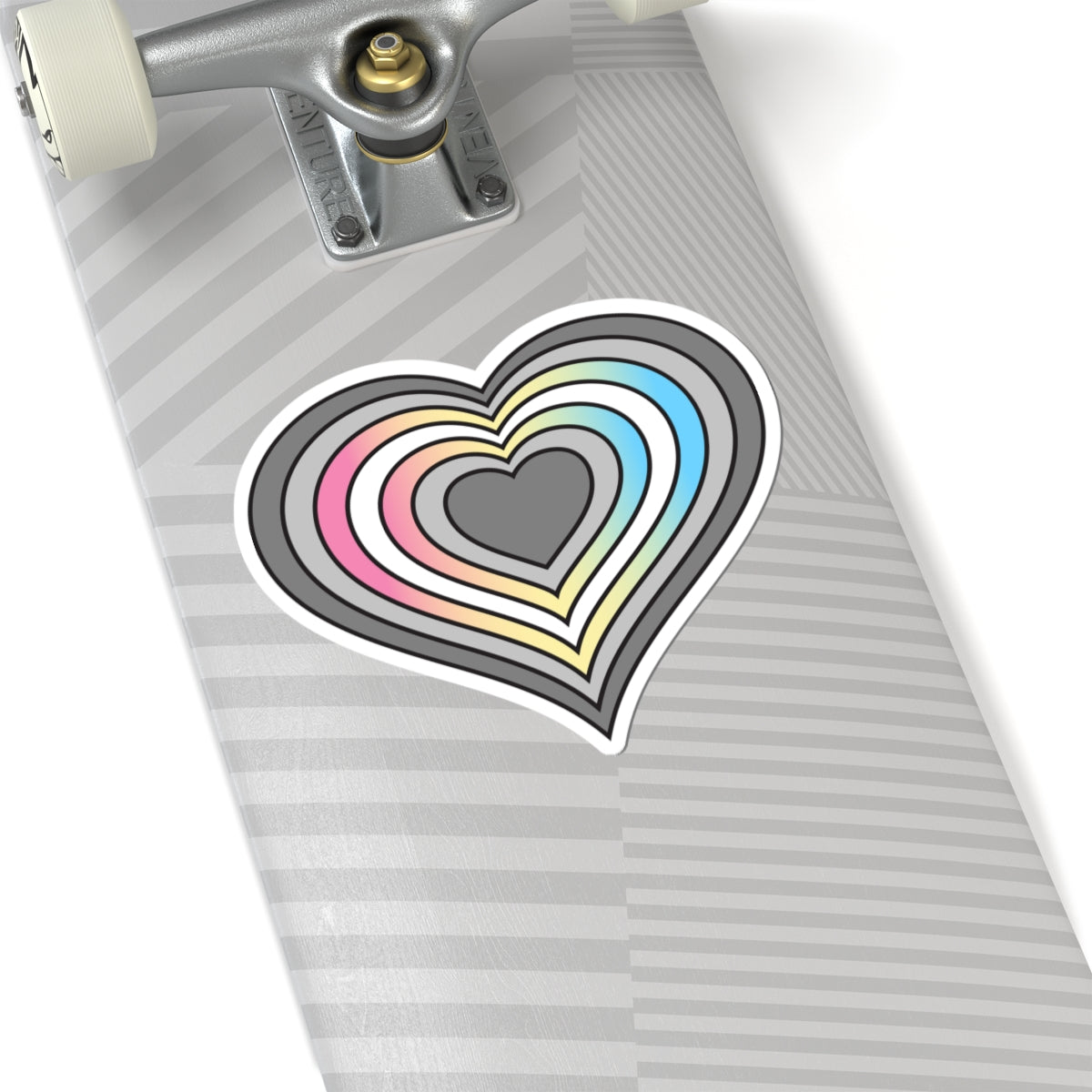 Close-up of the bottom of a silver skateboard featuring a 6 inch by 6 inch pride flag heart sticker in a Demifluid flag style applied to the surface.