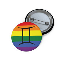 Front and back view of a circular rainbow pride flag button featuring the Gemini zodiac symbol in black centered on the front.