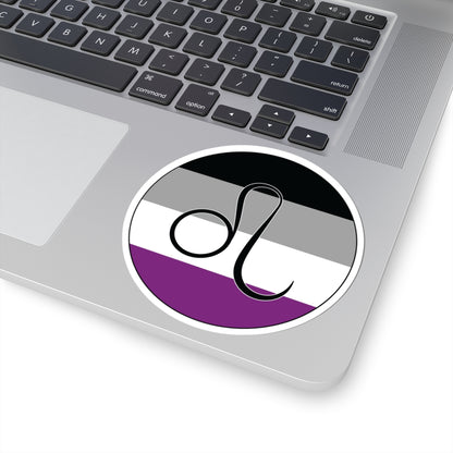 Close-up of the bottom right corner of a silver laptop featuring a 4 inch by 4 inch circular zodiac sticker with a centered Leo glyph on an Asexual pride flag style background applied to the surface.