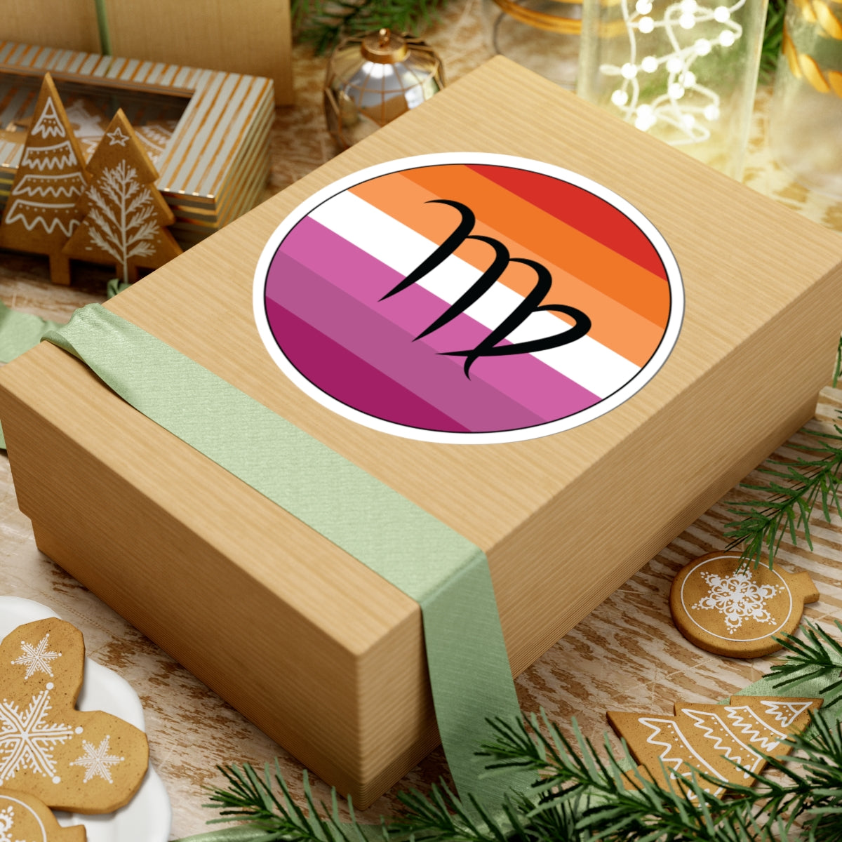 Gift box with a green ribbon on a festive background with cookies and Christmas decorations. Virgo Lesbian pride sticker centered on the box.