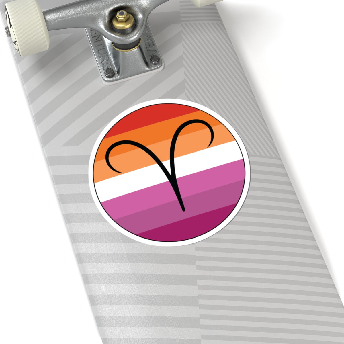 Close-up of the bottom of a silver skateboard featuring a 6 inch by 6 inch circular zodiac sticker with a centered Aires glyph on a Lesbian pride flag style background applied to the surface.