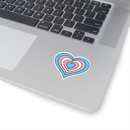 Close-up of the bottom right corner of a silver laptop featuring a 2 inch by 2 inch pride flag heart sticker in a Transgender flag style applied to the surface.