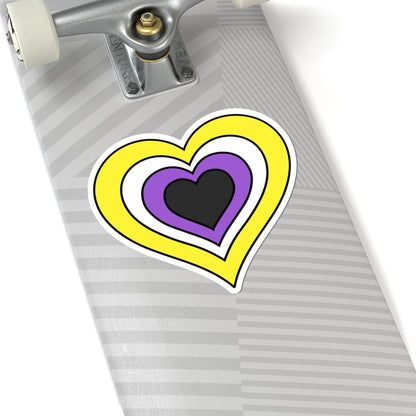 Close-up of the bottom of a silver skateboard featuring a 6 inch by 6 inch pride flag heart sticker in a Nonbinary flag style applied to the surface.