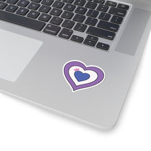 Close-up of the bottom right corner of a silver laptop featuring a 2 inches by 2 inches pride flag heart sticker in a Drag pride flag style applied to the surface.