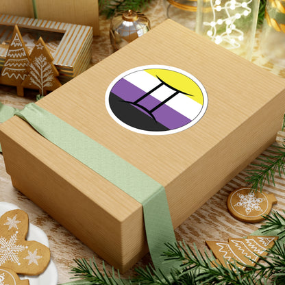 Gift box with a green ribbon on a festive background with cookies and Christmas decorations. Gemini Nonbinary pride sticker centered on the box.