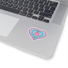 Close-up of the bottom right corner of a silver laptop featuring a 2 inch by 2 inch pride flag heart sticker in a Transmasc flag style applied to the surface.