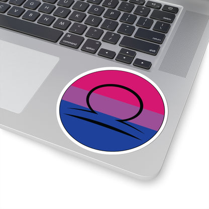 Close-up of the bottom right corner of a silver laptop featuring a 4 inch by 4 inch circular zodiac sticker with a centered Libra glyph on a Bisexual pride flag style background applied to the surface.