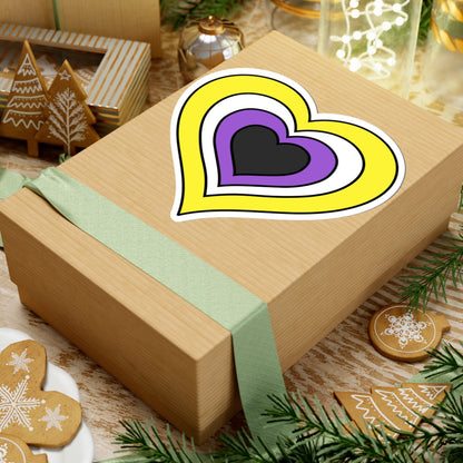Gift box with a green ribbon on a festive background with cookies and Christmas decorations. Heart-shaped Nonbinary pride sticker centered on the box.