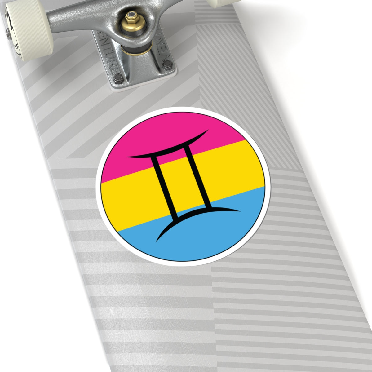 Close-up of the bottom of a silver skateboard featuring a 6 inch by 6 inch circular zodiac sticker with a centered Gemini glyph on a Pansexual pride flag style background applied to the surface.