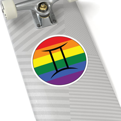 Close-up of the bottom of a silver skateboard featuring a 6 inch by 6 inch circular zodiac sticker with a centered Gemini glyph on a Rainbow pride flag style background applied to the surface.