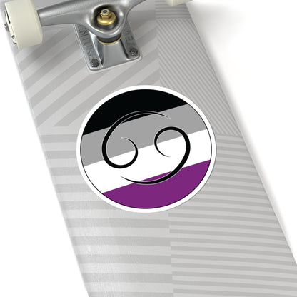Close-up of the bottom of a silver skateboard featuring a 6 inch by 6 inch circular zodiac sticker with a centered Cancer glyph on an Asexual pride flag style background applied to the surface.