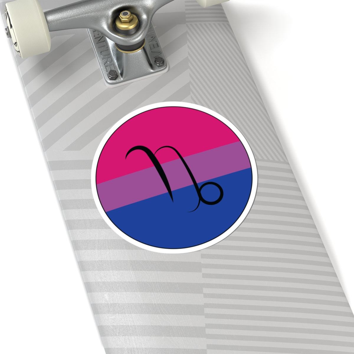 Close-up of the bottom of a silver skateboard featuring a 6 inch by 6 inch circular zodiac sticker with a centered Capricorn glyph on a Bisexual pride flag style background applied to the surface.