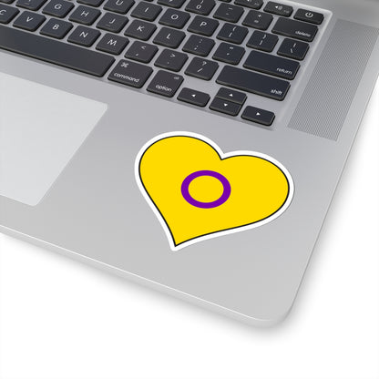 Close-up of the bottom right corner of a silver laptop featuring a 3 inch by 3 inch pride flag heart sticker in an Intersex flag style applied to the surface.