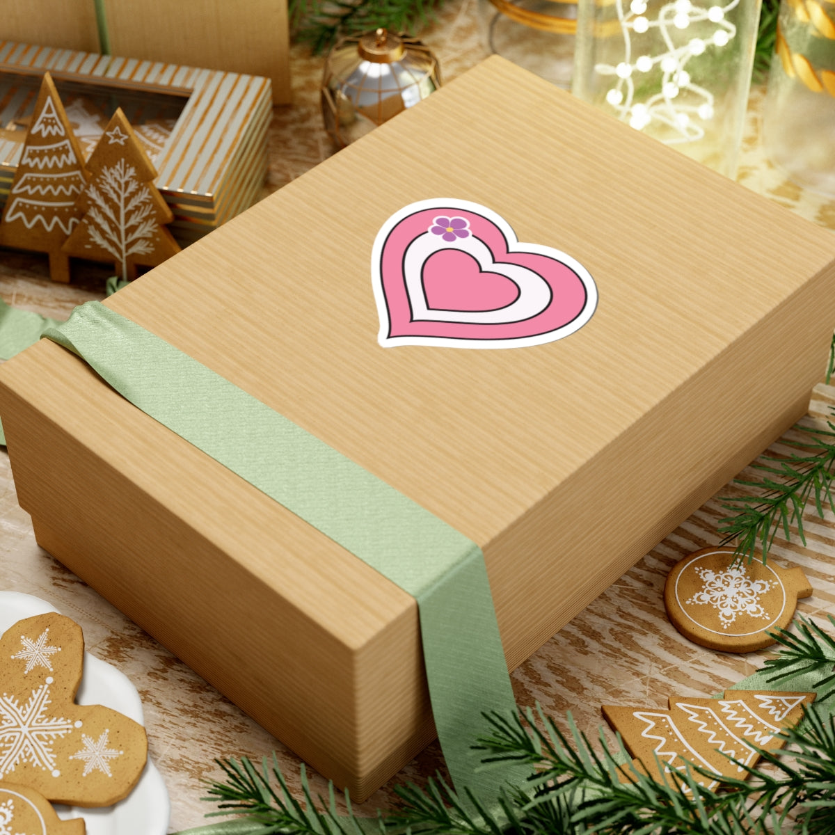 Gift box with a green ribbon on a festive background with cookies and Christmas decorations. Sapphic pride heart sticker centered on the box.