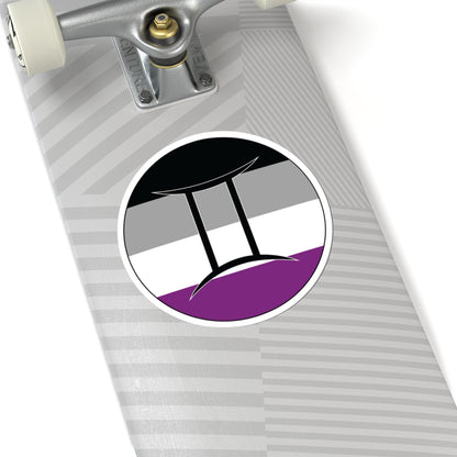 Close-up of the bottom of a silver skateboard featuring a 6 inch by 6 inch circular zodiac sticker with a centered Gemini glyph on an Asexual pride flag style background applied to the surface.