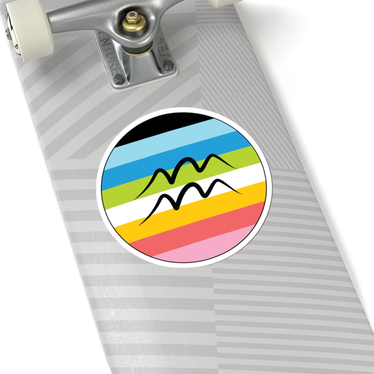 Close-up of the bottom of a silver skateboard featuring a 6 inch by 6 inch circular zodiac sticker with a centered Aquarius glyph on a Queer pride flag style background applied to the surface.