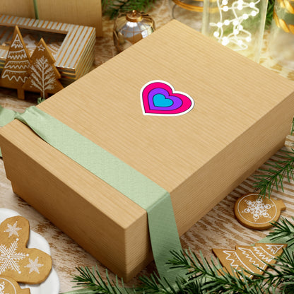 Gift box with a green ribbon on a festive background with cookies and Christmas decorations. Heart-shaped Androgyne pride sticker centered on the box.