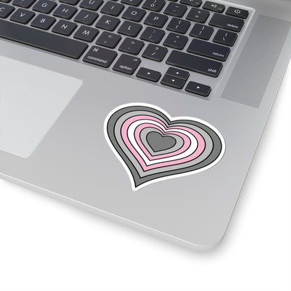 Close-up of the bottom right corner of a silver laptop featuring a 3 inch by 3 inch pride flag heart sticker in a Demigirl flag style applied to the surface.
