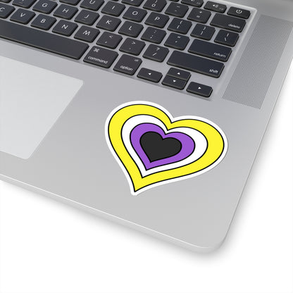 Close-up of the bottom right corner of a silver laptop featuring a 3 inch by 3 inch pride flag heart sticker in a Nonbinary flag style applied to the surface.