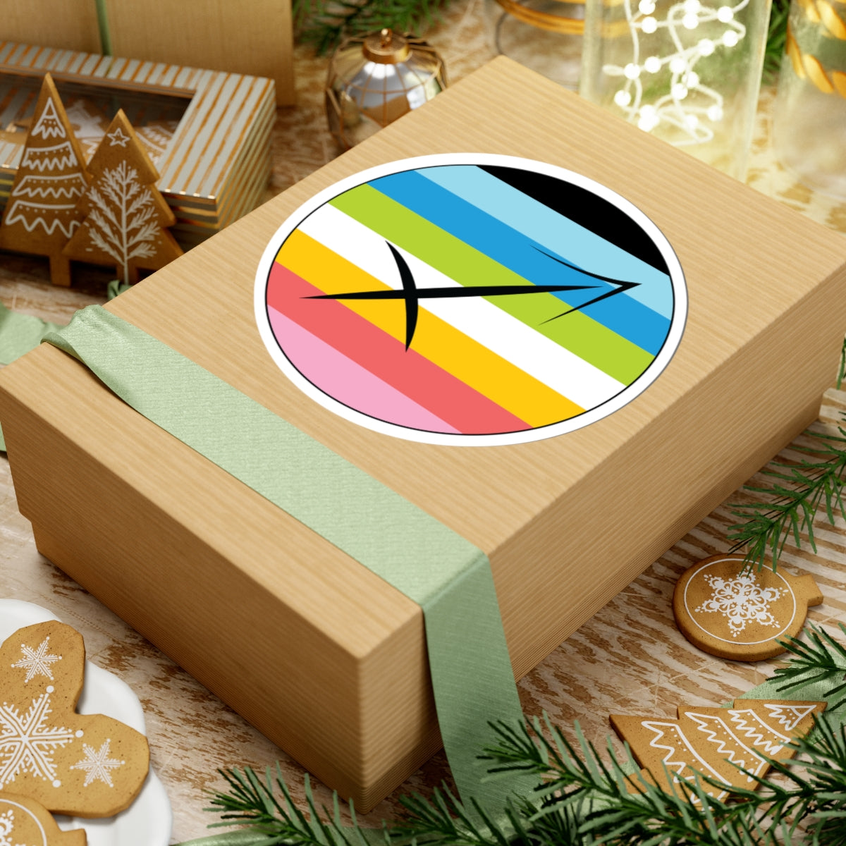 Gift box with a green ribbon on a festive background with cookies and Christmas decorations. Sagittarius Queer pride sticker centered on the box.