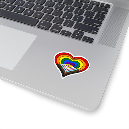 Close-up of the bottom right corner of a silver laptop featuring a 2 inch by 2 inch pride flag heart sticker in an Intersex-Inclusive Progress pride flag style applied to the surface.