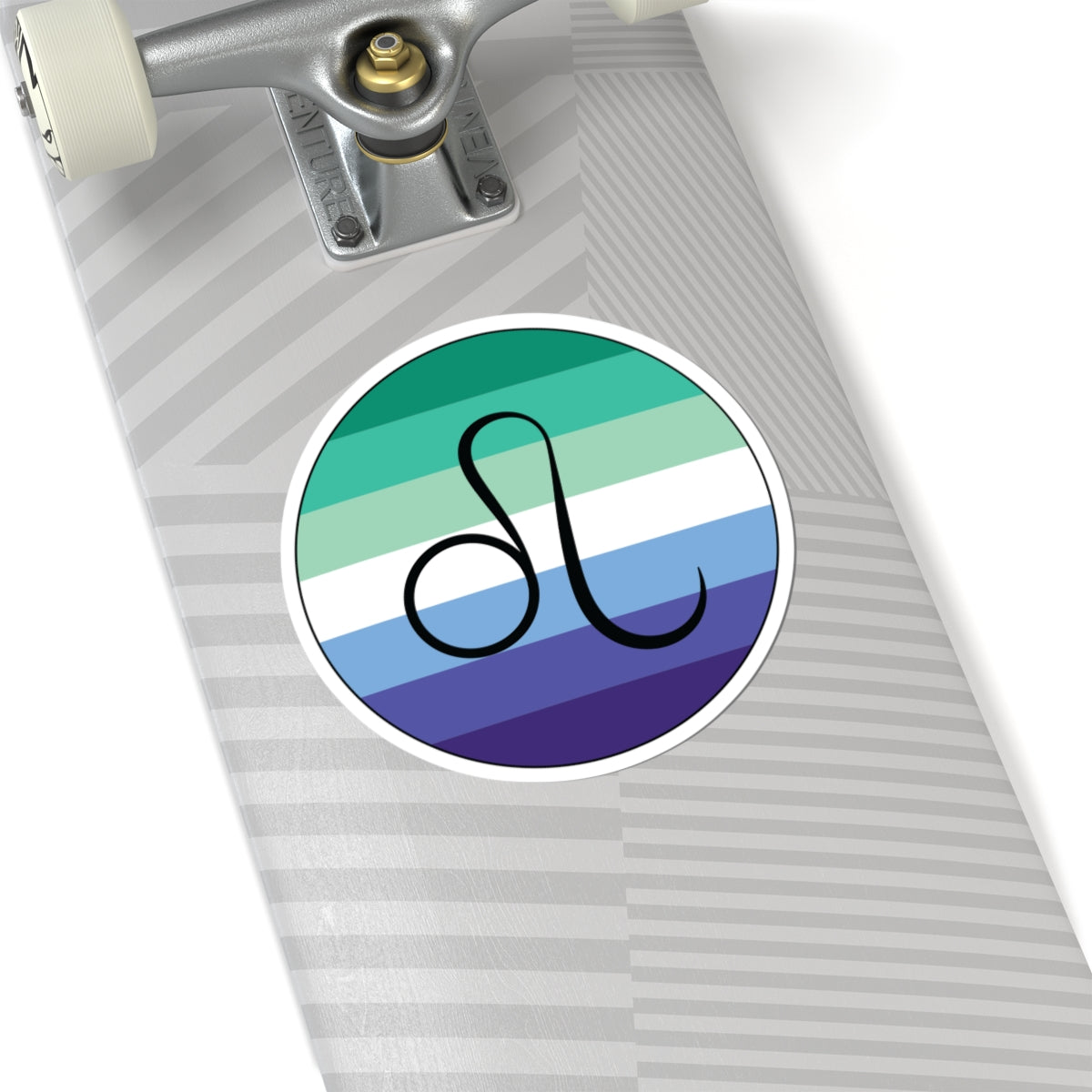 Close-up of the bottom of a silver skateboard featuring a 6 inch by 6 inch circular zodiac sticker with a centered Leo glyph on a Gay Men pride flag style background applied to the surface.