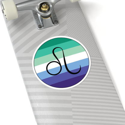 Close-up of the bottom of a silver skateboard featuring a 6 inch by 6 inch circular zodiac sticker with a centered Leo glyph on a Gay Men pride flag style background applied to the surface.