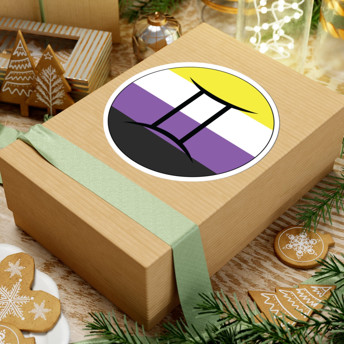 Gift box with a green ribbon on a festive background with cookies and Christmas decorations. Gemini Nonbinary pride sticker centered on the box.