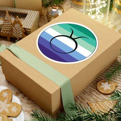 Gift box with a green ribbon on a festive background with cookies and Christmas decorations. Taurus Gay Men pride sticker centered on the box.