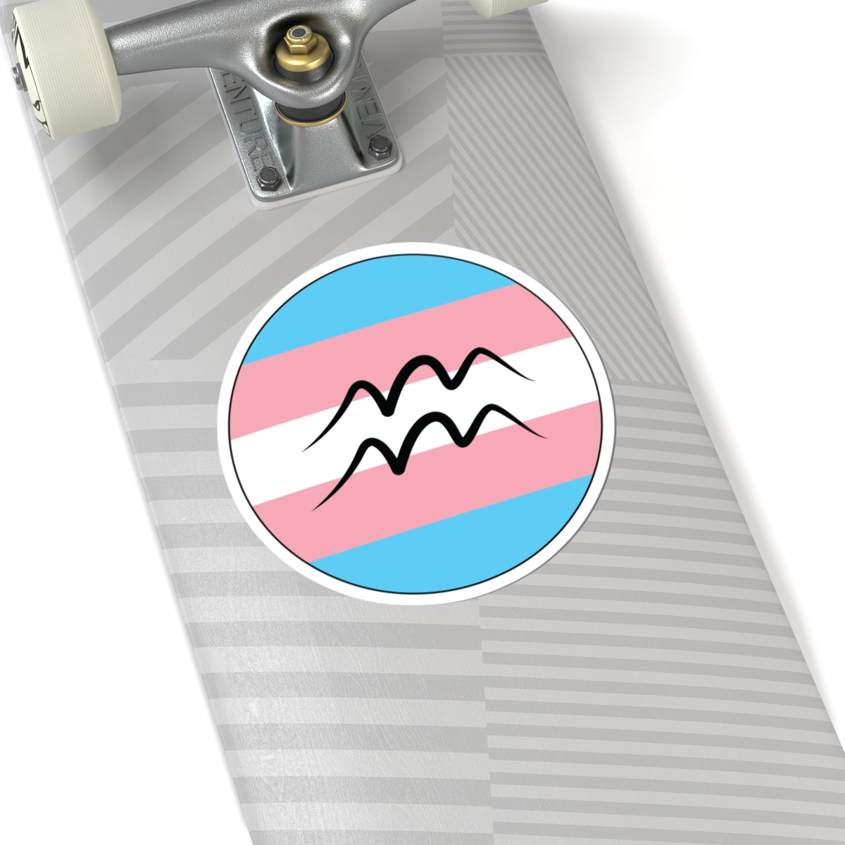Close-up of the bottom of a silver skateboard featuring a 6 inch by 6 inch circular zodiac sticker with a centered Aquarius glyph on a Transgender pride flag style background applied to the surface.