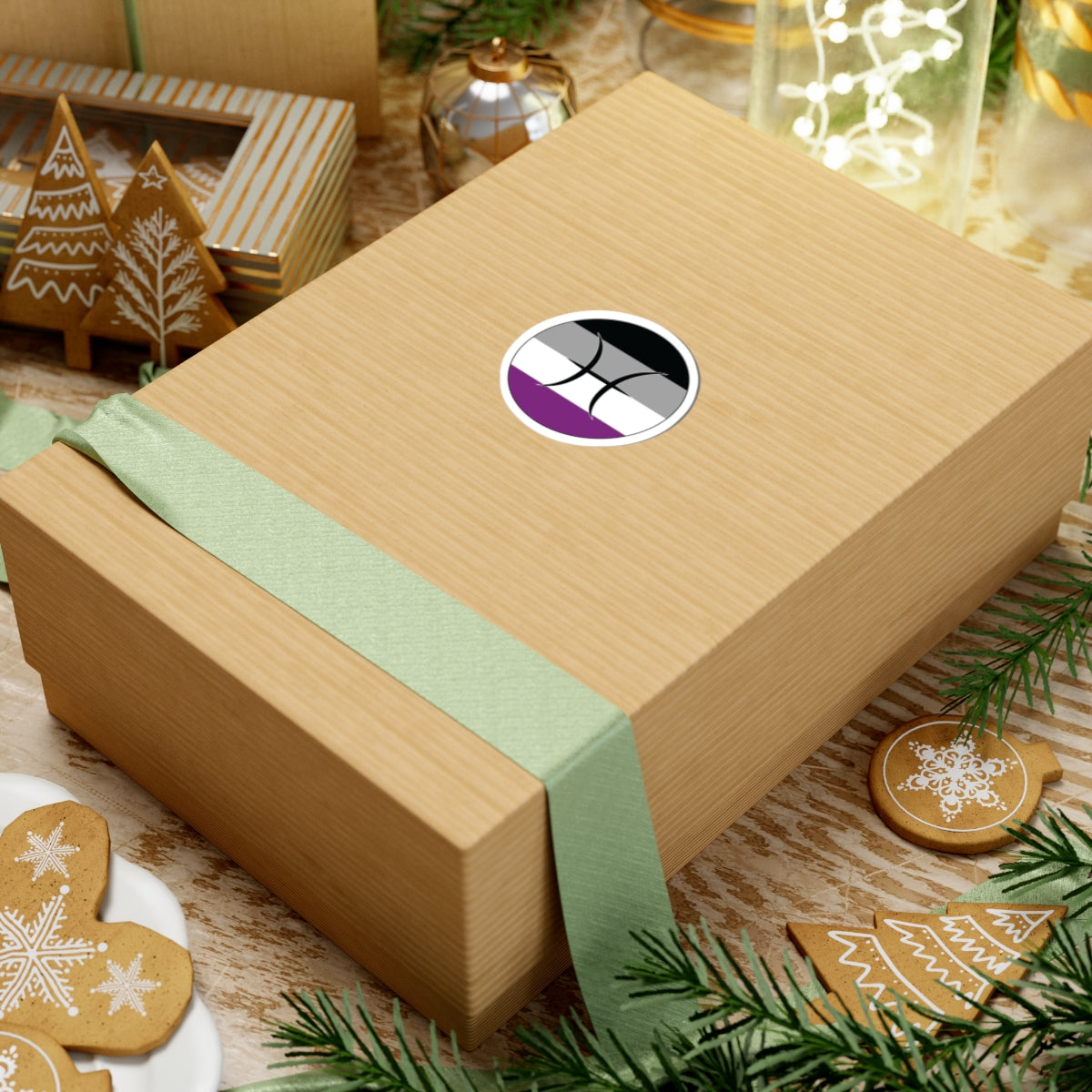 Gift box with a green ribbon on a festive background with cookies and Christmas decorations. Pisces Asexual pride sticker centered on the box.