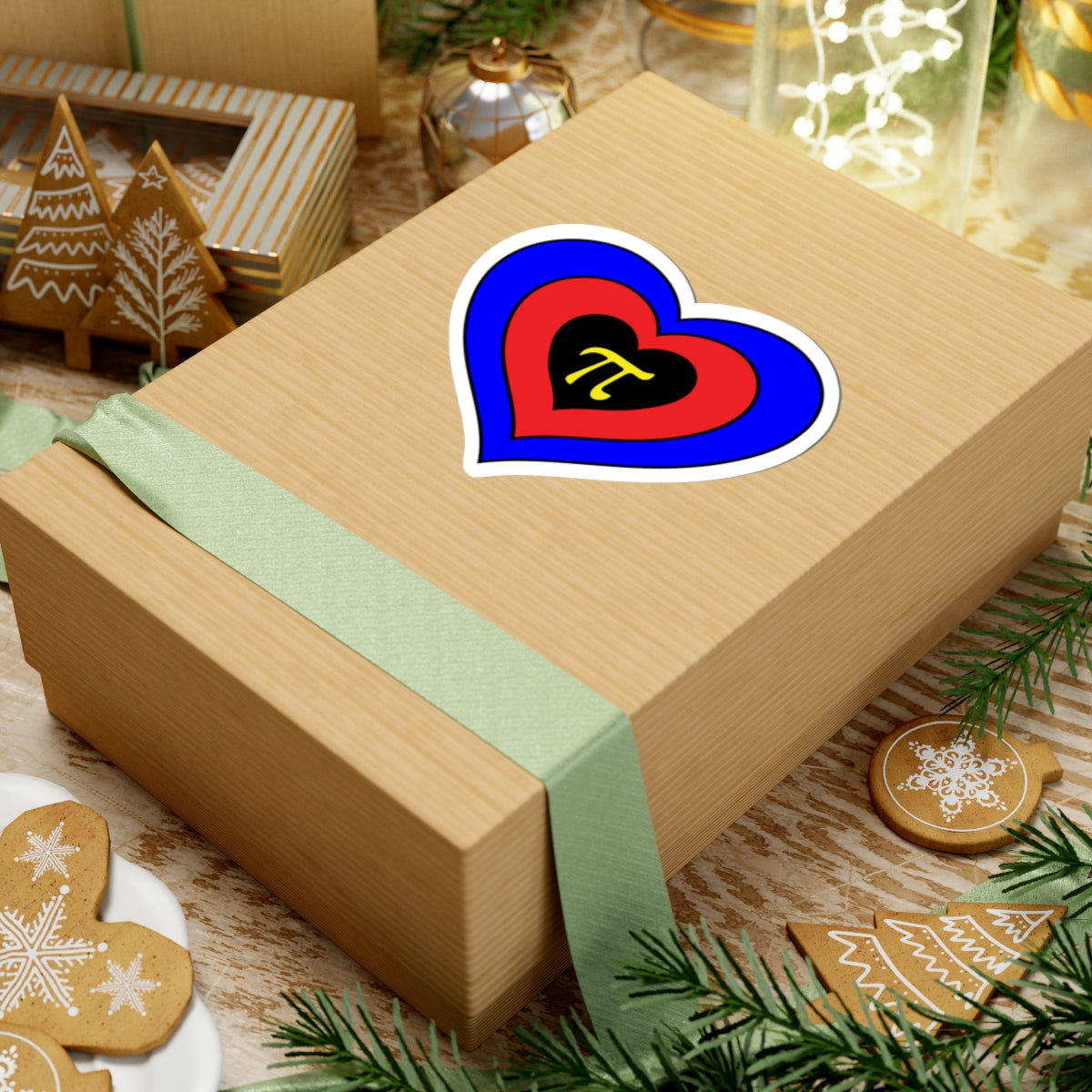 Gift box with a green ribbon on a festive background with cookies and Christmas decorations. Heart-shaped Polyamory pride sticker centered on the box.