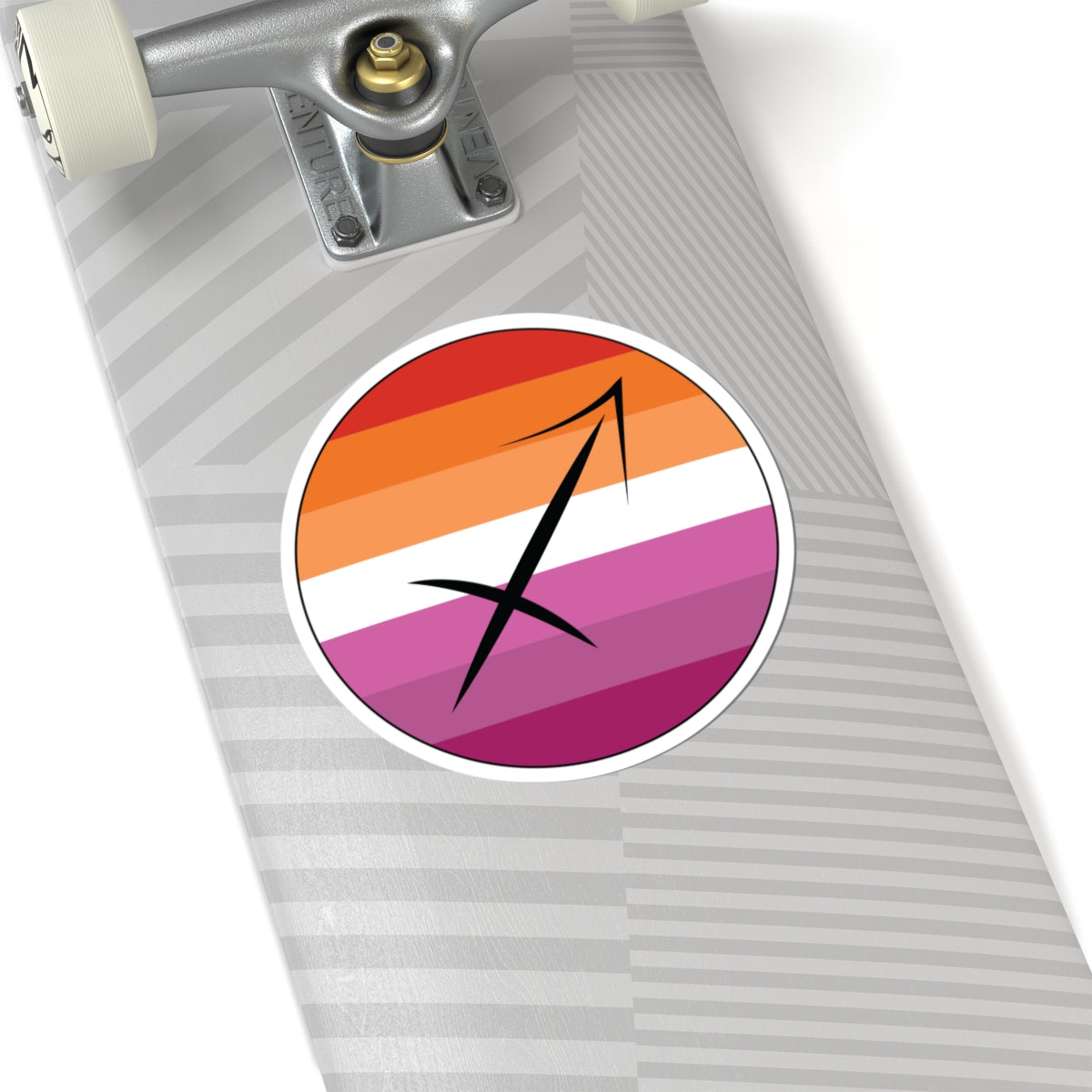 Close-up of the bottom of a silver skateboard featuring a 6 inch by 6 inch circular zodiac sticker with a centered Sagittarius glyph on a Lesbian pride flag style background applied to the surface.