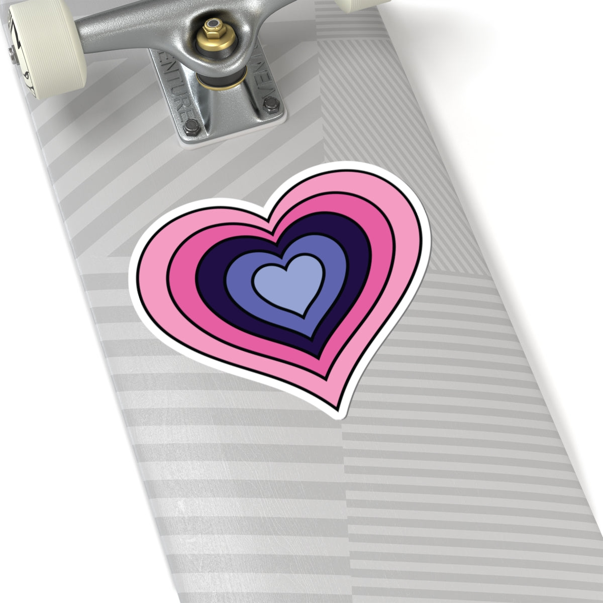 Close-up of the bottom of a silver skateboard featuring a 6 inch by 6 inch pride flag heart sticker in an Omnigender flag style applied to the surface.