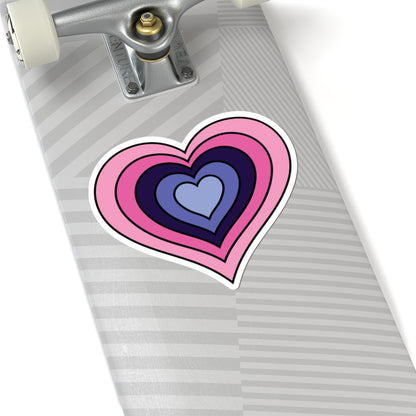 Close-up of the bottom of a silver skateboard featuring a 6 inch by 6 inch pride flag heart sticker in an Omnigender flag style applied to the surface.