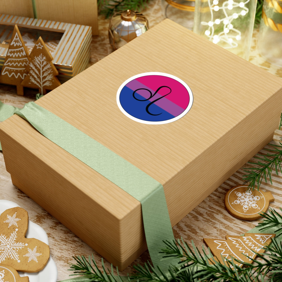Gift box with a green ribbon on a festive background with cookies and Christmas decorations. Leo Bisexual pride sticker centered on the box.