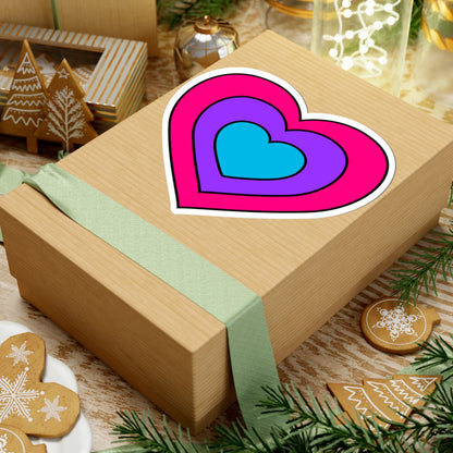 Gift box with a green ribbon on a festive background with cookies and Christmas decorations. Heart-shaped Androgyne pride sticker centered on the box.