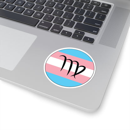 Close-up of the bottom right corner of a silver laptop featuring a 3 inch by 3 inch circular zodiac sticker with a centered Virgo glyph on a Transgender pride flag style background applied to the surface.