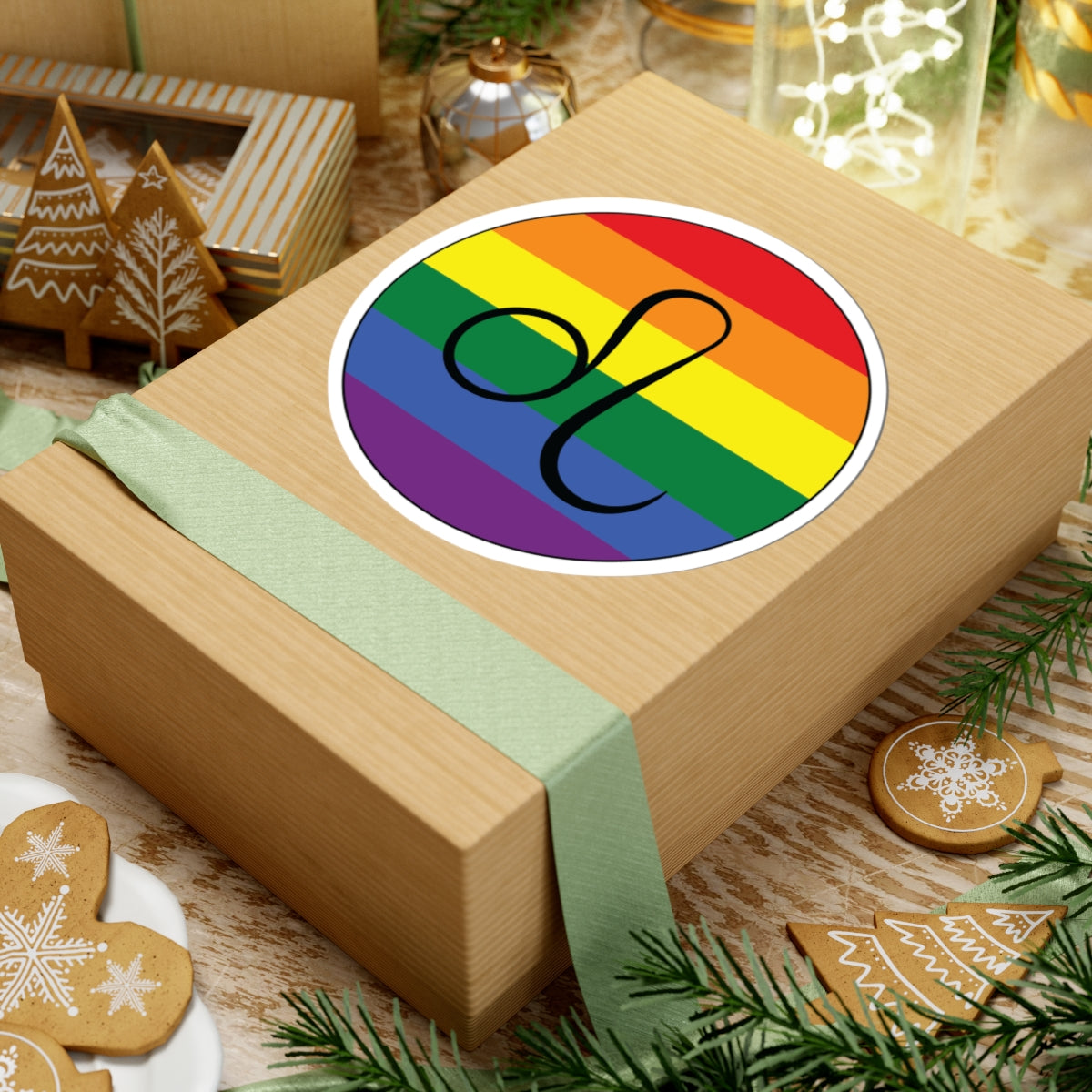 Gift box with a green ribbon on a festive background with cookies and Christmas decorations. Leo Rainbow pride sticker centered on the box.