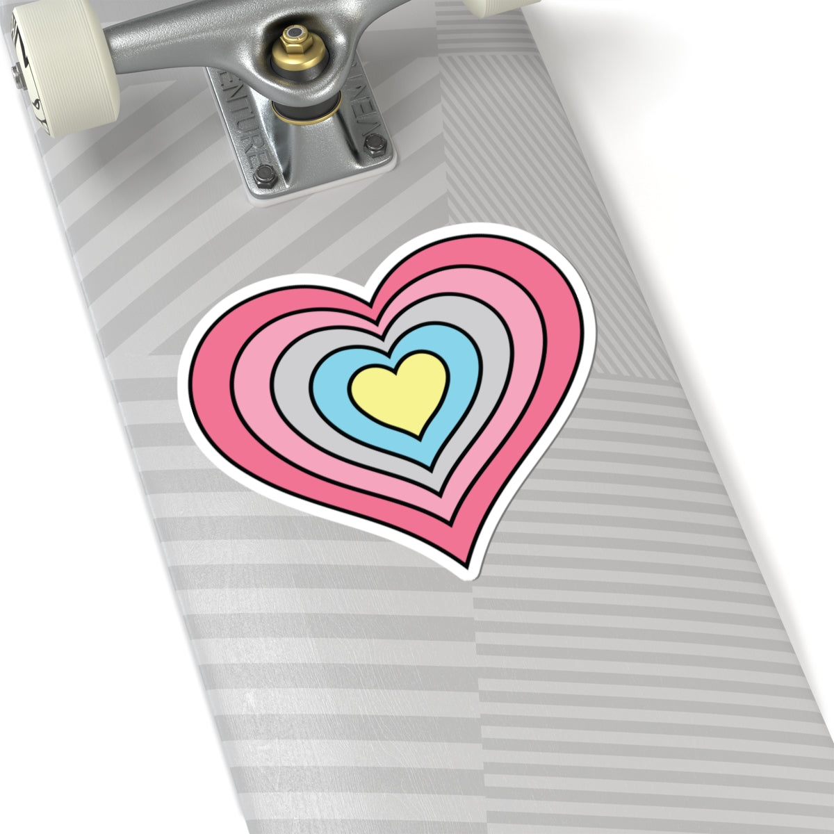 Close-up of the bottom of a silver skateboard featuring a 6 inch by 6 inch pride flag heart sticker in a Genderflux flag style applied to the surface.