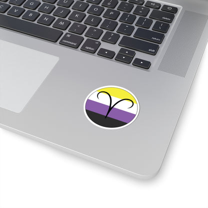 Close-up of the bottom right corner of a silver laptop featuring a 2 inch by 2 inch circular zodiac sticker with a centered Aires glyph on a Nonbinary pride flag style background applied to the surface.