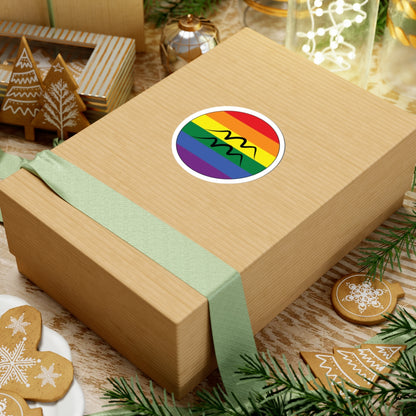 Gift box with a green ribbon on a festive background with cookies and Christmas decorations. Aquarius Rainbow pride sticker centered on the box.